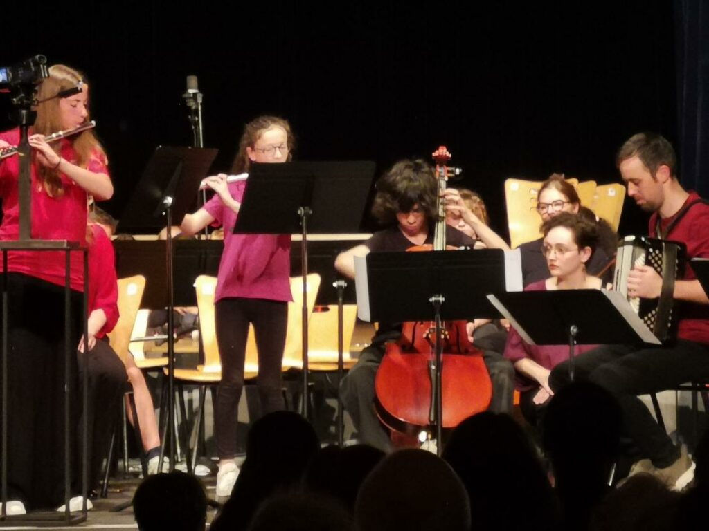 Spectacle de musique avec des élèves jouant sur scène de la flute traversière, du violoncelle, de l'accordéon.